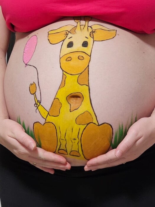 A drawn giraffe on the stomach of a pregnant woman